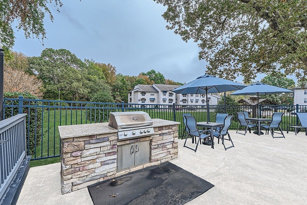 A patio with a stone fireplace and chairs.