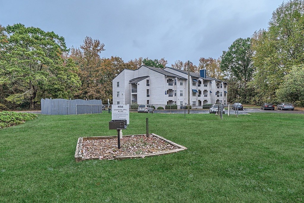 A sign is placed in a flower bed in front of a building.