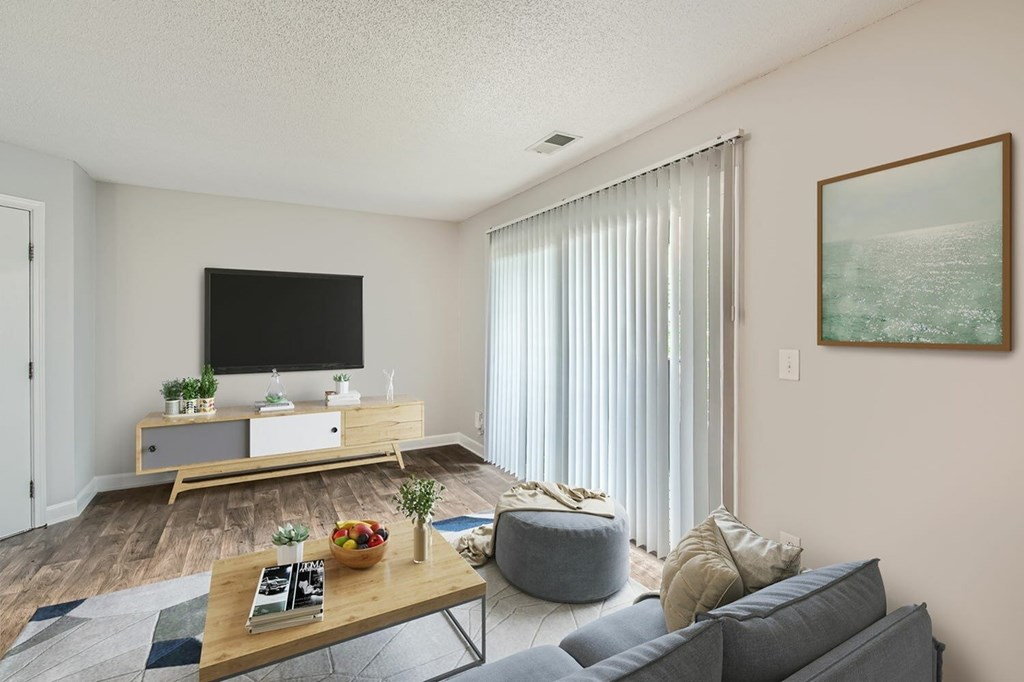 A living room with a grey couch, a wooden coffee table, a flat screen TV, and a painting on the wall.
