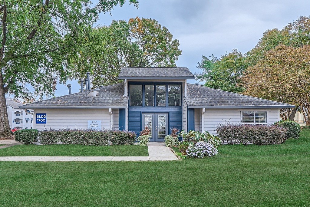 A house with a blue door and a sign that says "For Sale" is surrounded by greenery.