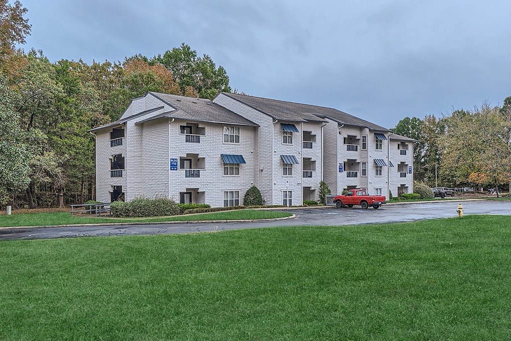 A large apartment complex with a red car parked in front.
