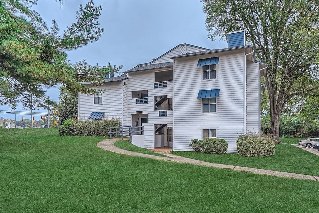 A two-story apartment building with a green lawn in front.