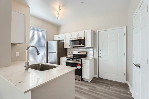 A kitchen with white cabinets and a sink.