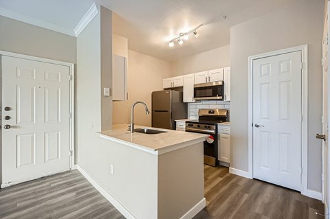 A kitchen with white cabinets and a white door.