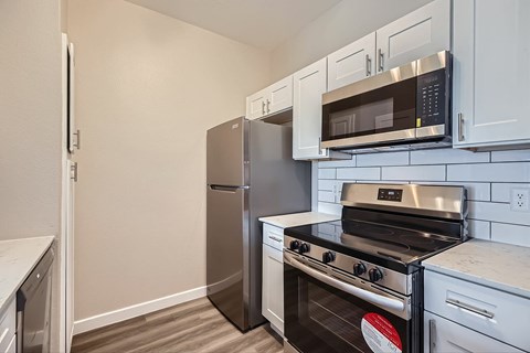 A kitchen with a stainless steel refrigerator, microwave, and oven.