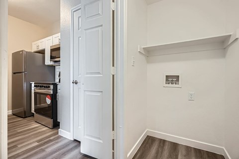 A white door is open to a kitchen with a stove and oven.