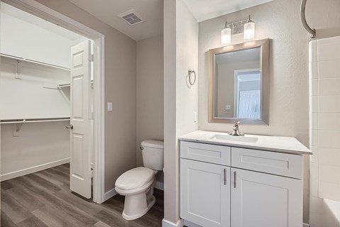 A white bathroom with a toilet, sink, and mirror.