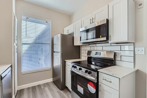 A kitchen with a black stove top oven and a microwave above it.