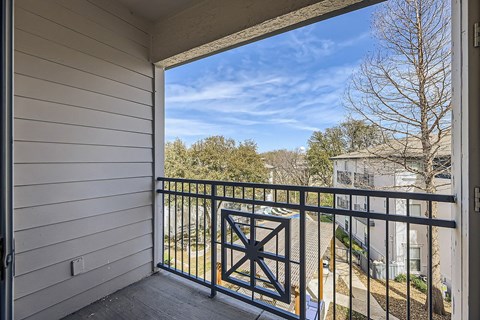 A balcony with a black railing and a view of a tree and a building.
