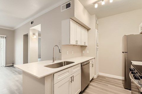 A kitchen with a sink, refrigerator, and cabinets.