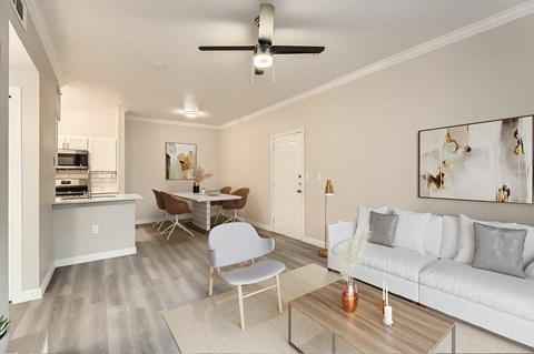 A modern living room with a white couch, a dining table, and a ceiling fan.