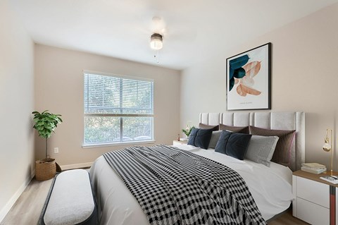 A bedroom with a large bed and a window with blinds.