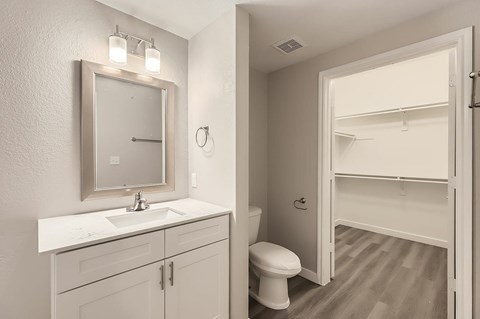 A bathroom with a toilet, sink, and mirror.