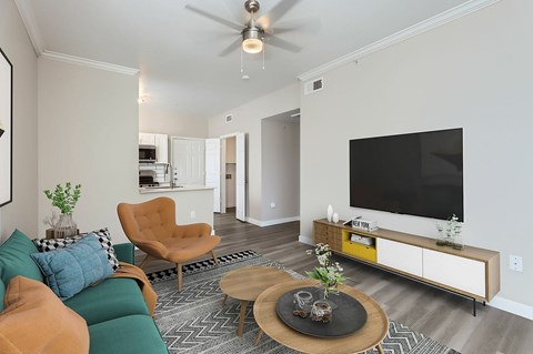 A living room with a green couch, a brown chair, a wooden coffee table, and a flat screen TV mounted on the wall.
