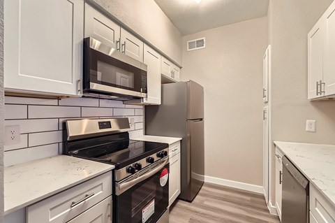A kitchen with white cabinets and black appliances.