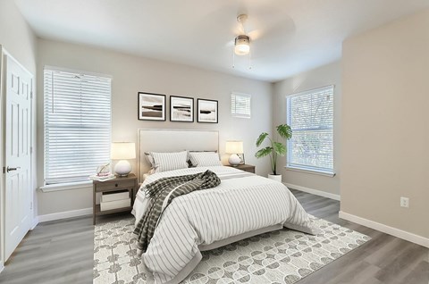 A bedroom with a large bed and a window with blinds.