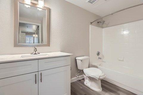 A white toilet sits in a bathroom next to a sink and a mirror.