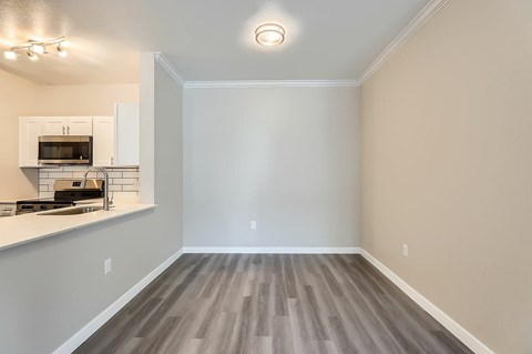 A room with a kitchen area and a wood floor.