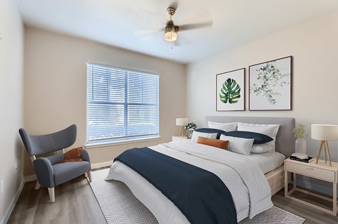 A bedroom with a bed, chair, and two framed pictures on the wall.