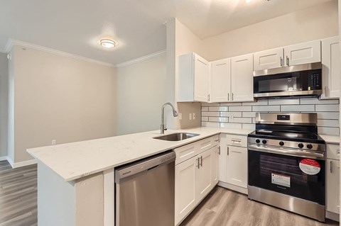 A kitchen with a stove, sink, and microwave.
