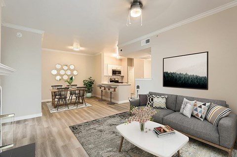 A living room with a grey couch, a white coffee table, and a painting on the wall.