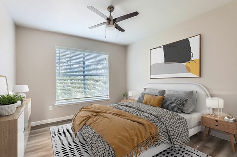A bedroom with a bed, a ceiling fan, and a painting on the wall.