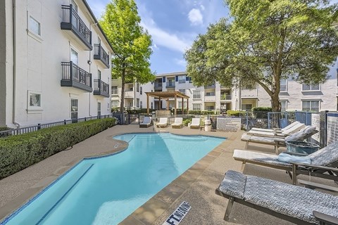 A swimming pool surrounded by lounge chairs and trees.