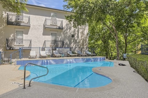 A small pool in front of a building with a balcony.