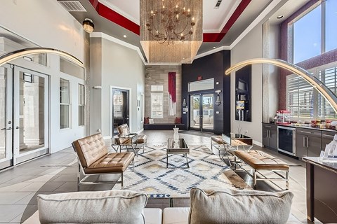 A large, modern living room with a chandelier and a kitchen area in the background.