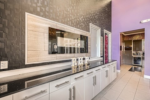 A kitchen with white cabinets and a black and white tiled backsplash.