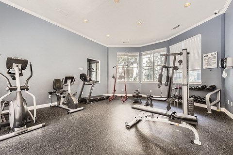 A spacious gym with a variety of equipment including a stationary bike, treadmill, and weight machines.