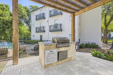 A grill is in front of a sign that says "Rise Grill Rules".