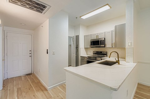A kitchen with a white counter top and a white door.