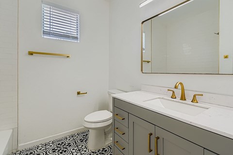A bathroom with a toilet, sink, and mirror.