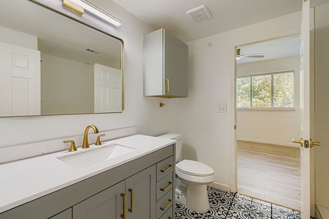 A bathroom with a sink, toilet and a mirror.