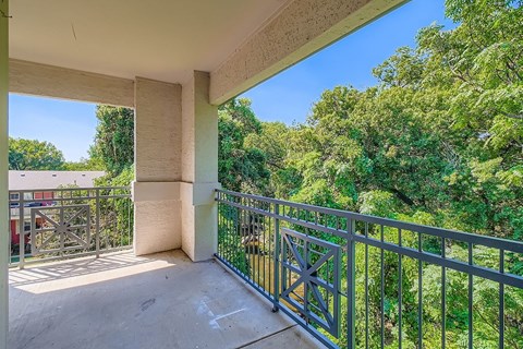 A balcony with a metal railing and a view of trees.