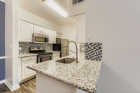 A kitchen with a granite counter top and a sink.