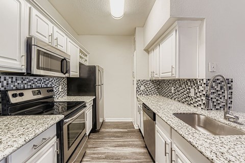 A kitchen with white cabinets and a black and white checkered backsplash.