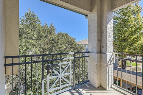 A balcony with a metal railing and a view of trees.