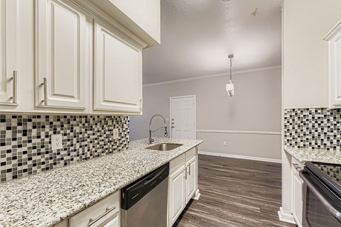 A kitchen with white cabinets and a black and white checkered backsplash.