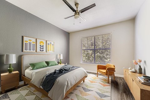 A bedroom with a bed, a chair, a ceiling fan, and a window with blinds.