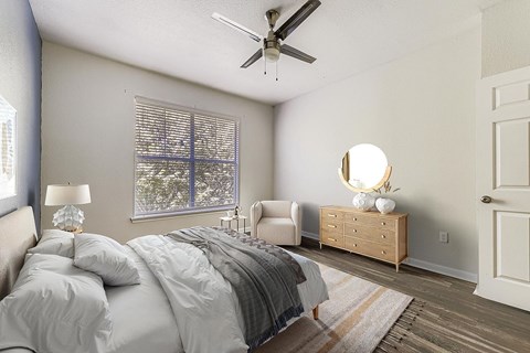 A bedroom with a bed, a chair, a dresser, and a ceiling fan.
