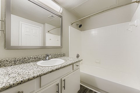 A bathroom with a granite countertop and white fixtures.