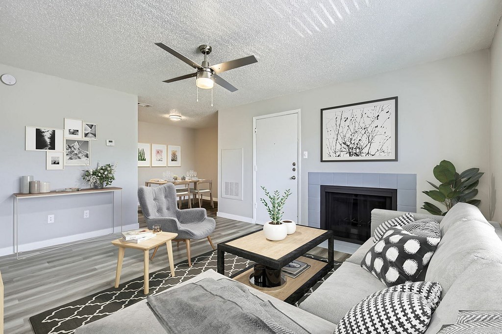 A living room with a grey couch, a coffee table, a fireplace, and a ceiling fan.