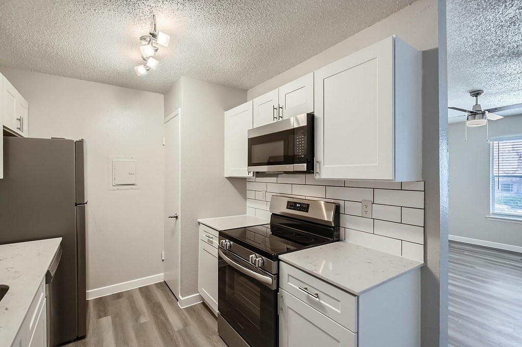 A kitchen with white cabinets and black appliances.