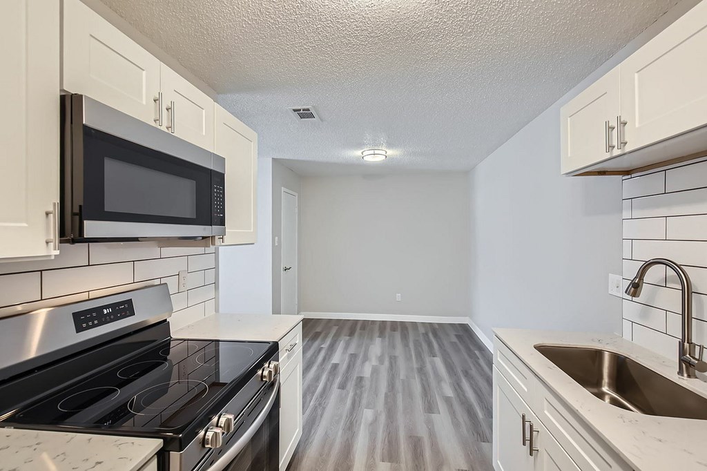 A kitchen with a black stove top oven and white cabinets.