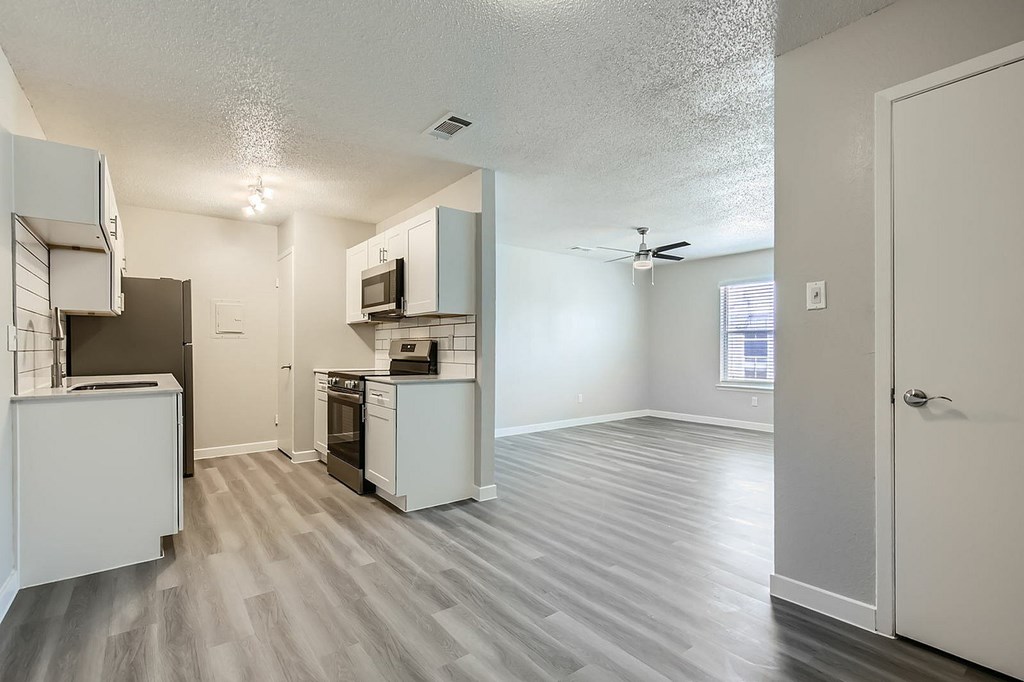 A kitchen with white appliances and a wood floor.