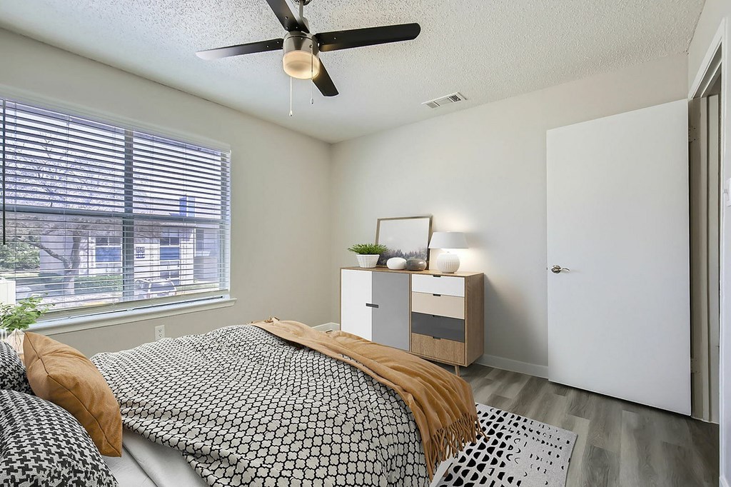 A bedroom with a bed, a ceiling fan, and a window with blinds.