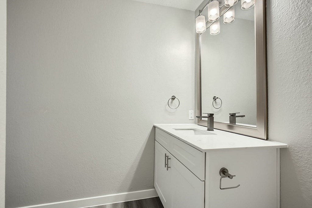 A white bathroom vanity with a mirror and lights above it.