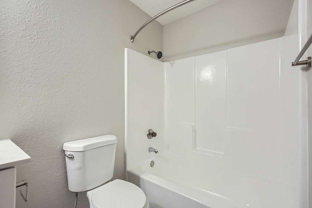 A white toilet sits next to a white bathtub in a small bathroom.